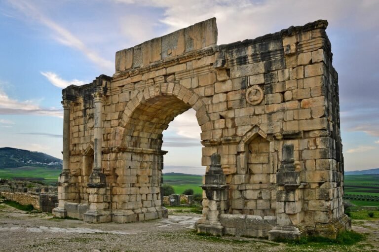 Stunning view of the ancient Roman arch in Volubilis, Morocco amid a serene landscape.