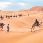Tourists ride camels across the scenic sand dunes of Merzouga, Morocco.