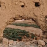 View of Ouarzazate through a traditional mudbrick wall, showcasing historic architecture.