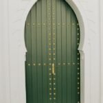 Elegant green Moroccan door with decorative arch in Casablanca, exhibiting rich cultural architecture.