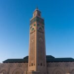 Stunning view of the Hassan II Mosque tower in Casablanca, Morocco against a clear blue sky.