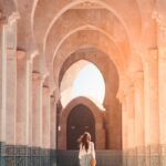 A woman walks through the stunning arches of Hassan II Mosque, Casablanca, highlighting Islamic architecture.