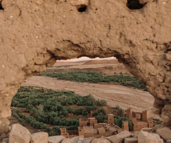 View of Ouarzazate through a traditional mudbrick wall, showcasing historic architecture.