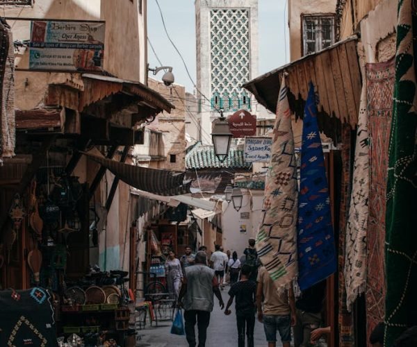 Explore the bustling narrow alley of a Moroccan bazaar with shops and vibrant textiles.