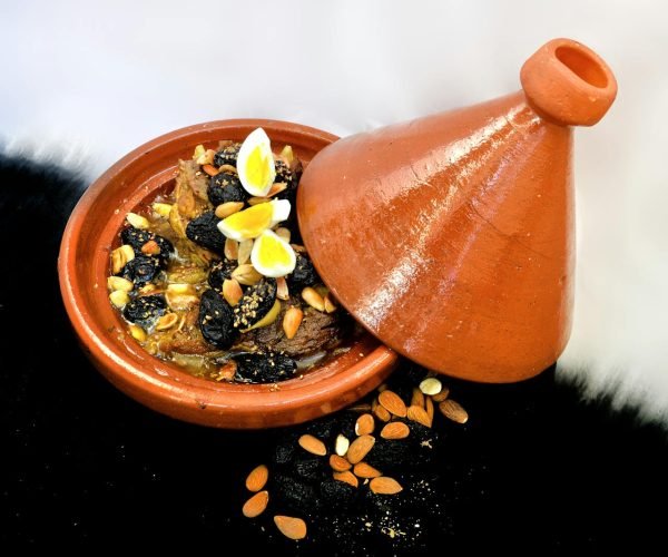 Delicious Moroccan lamb tagine with almonds, prunes, and quail eggs in a clay pot.