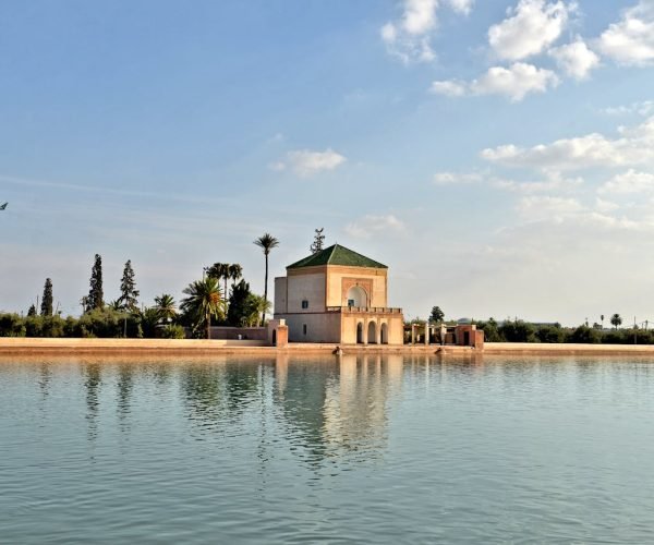 Scenic view of Menara Gardens pavilion reflecting in a tranquil lake in Marrakech, Morocco.