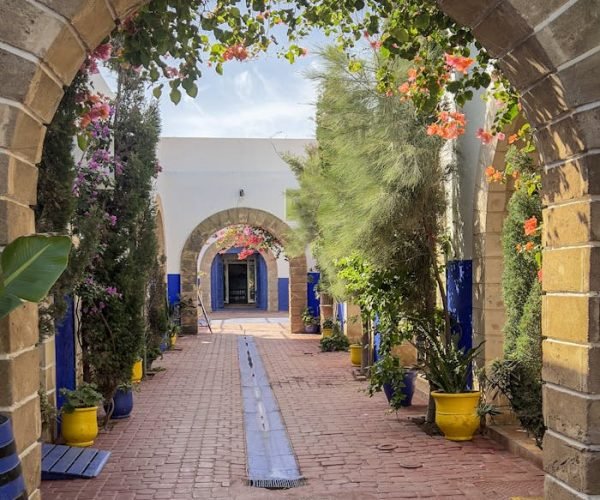 Charming archway in Essaouira Medina with vibrant flowers and traditional architecture.